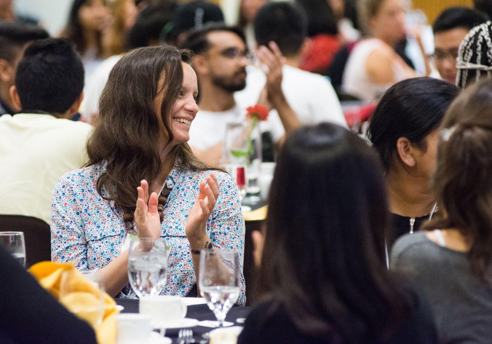 Woman smiling and clapping at conference