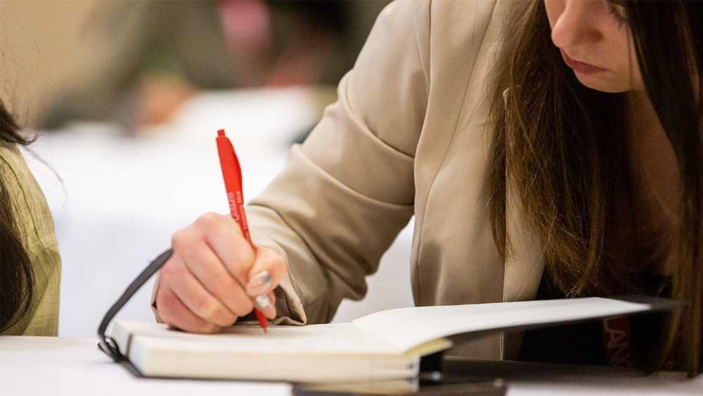 Lang Masters in Leadership student writing in a notebook.