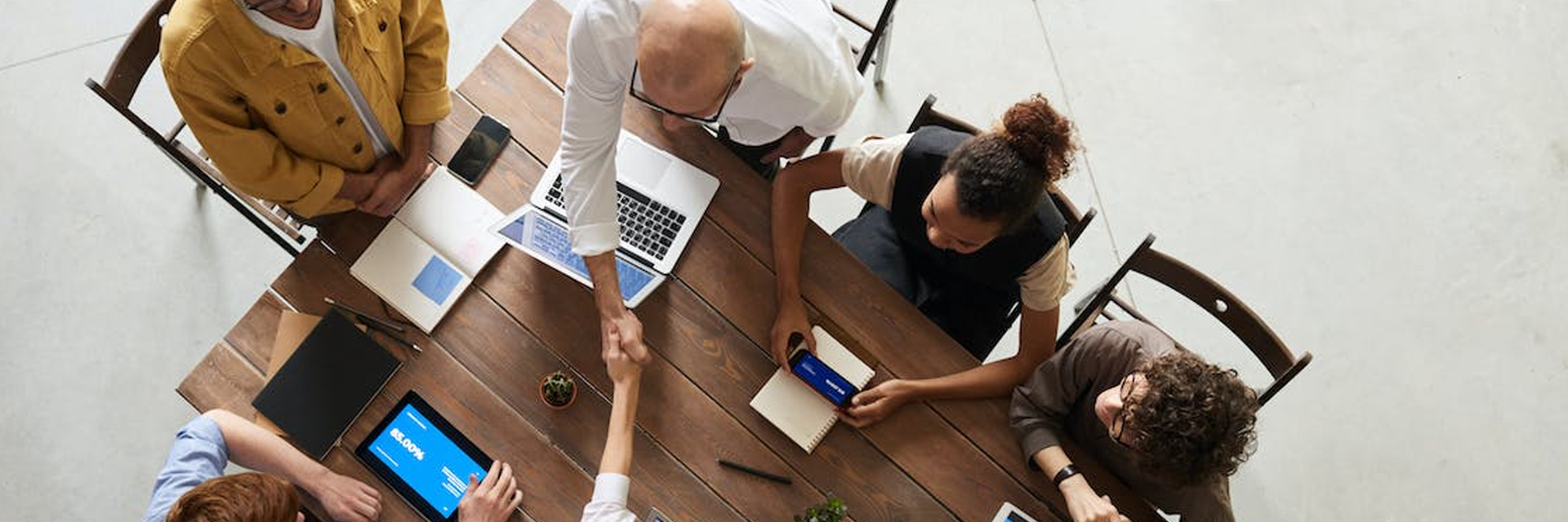 photo of employee shaking hands with another employee at a table