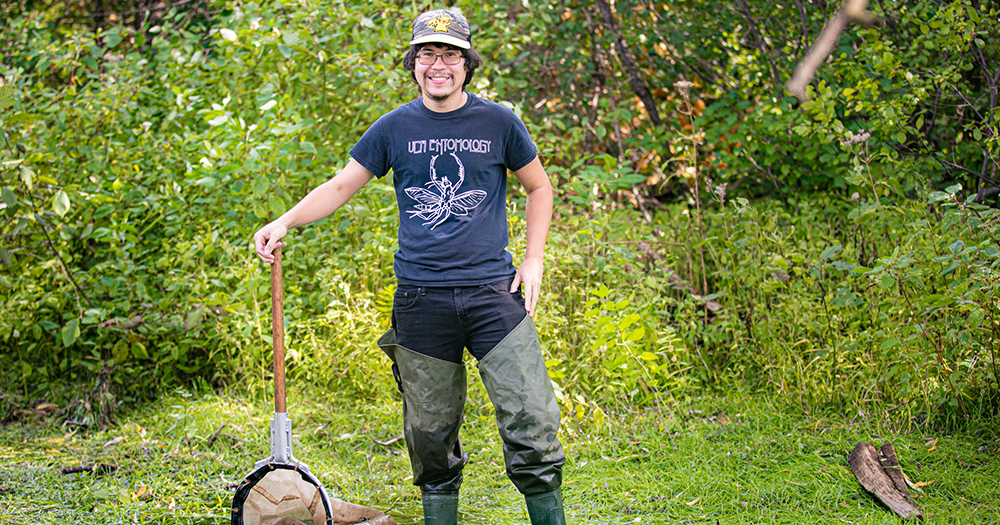 a student holding a net in a marshy area