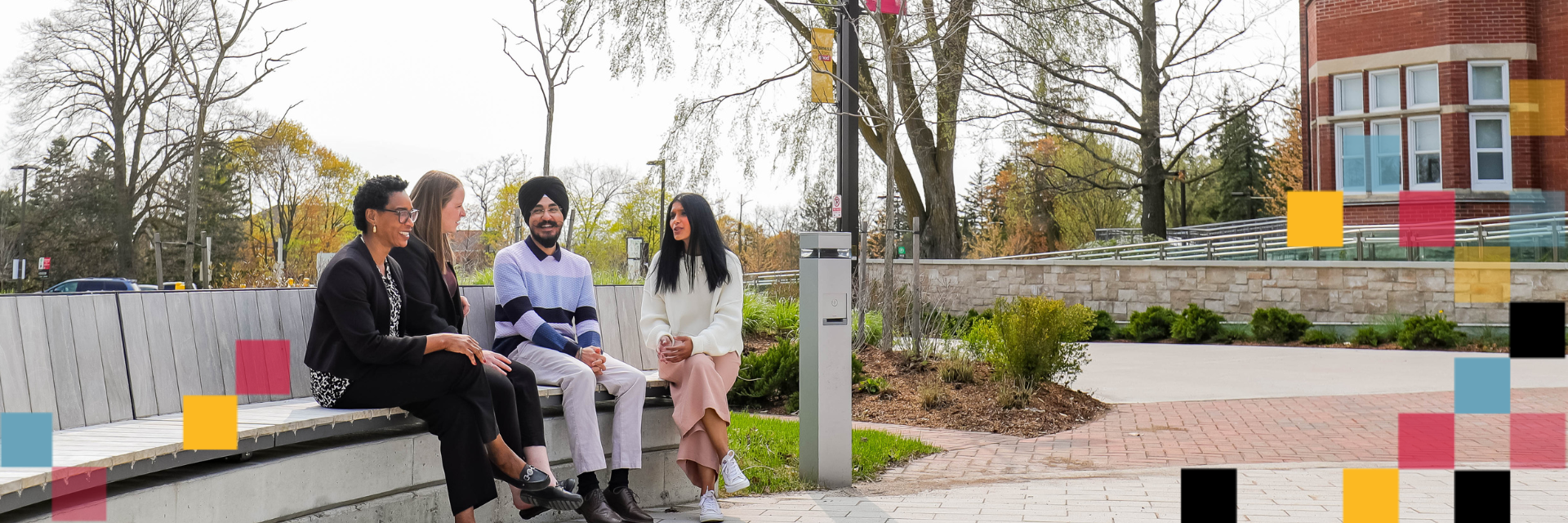 Four people sitting on a bench talking in Lang Plaza.