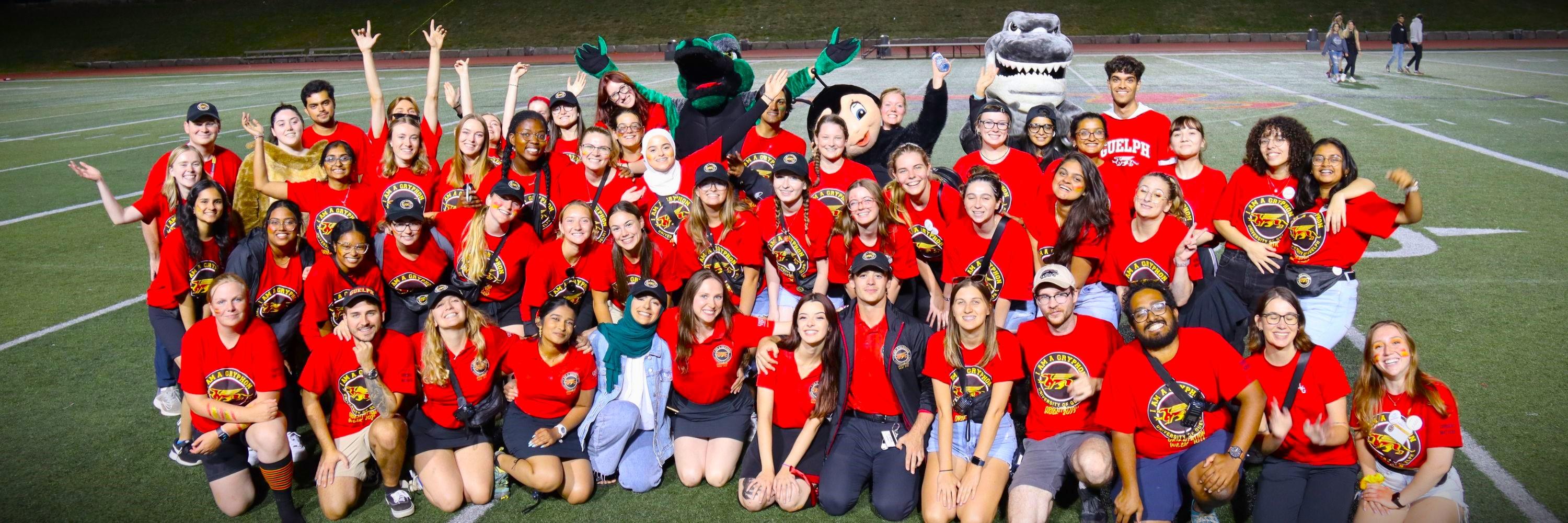 Image of a group of students grouped together on the Football Field wearing red t-shirts.