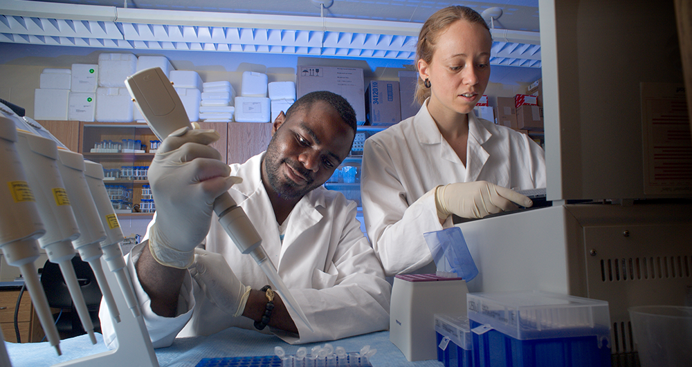 two students working in a lab, inspecting a specimen