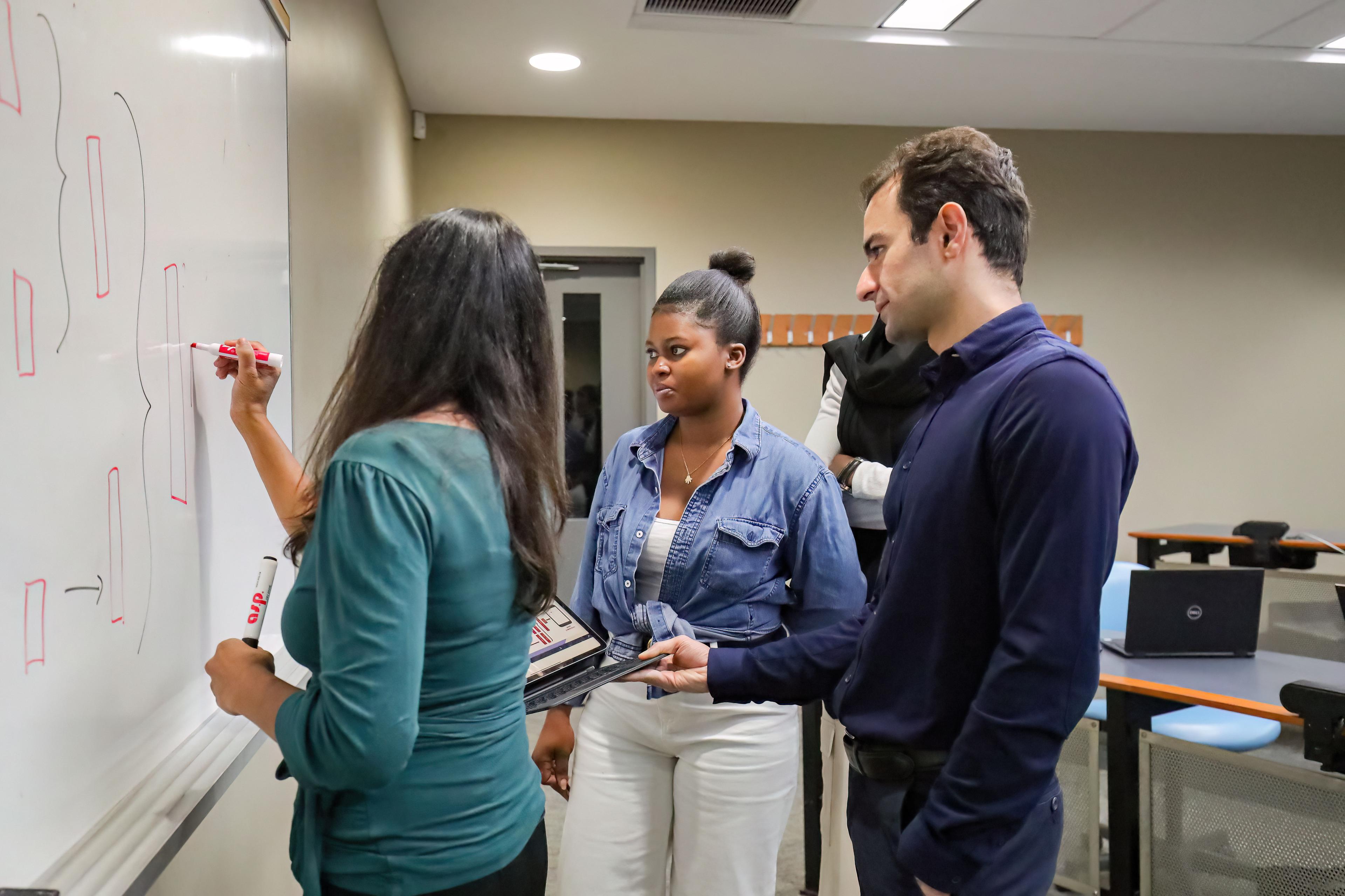 Teacher at white board with two students.