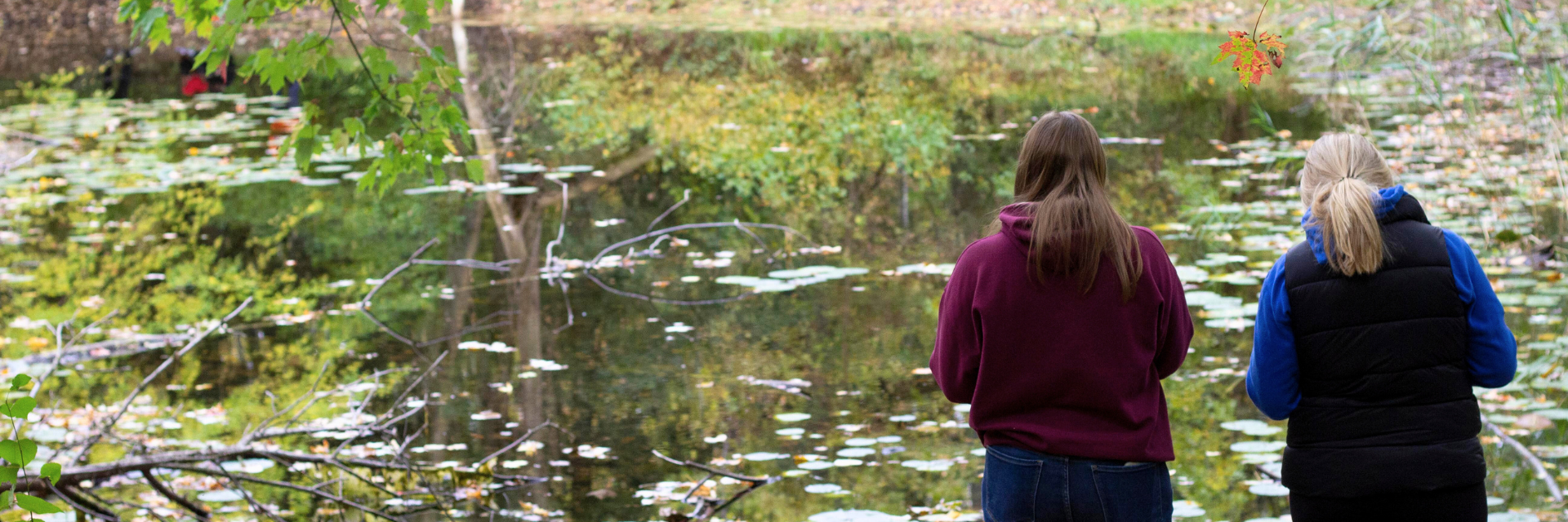 Two students standing next to a pond