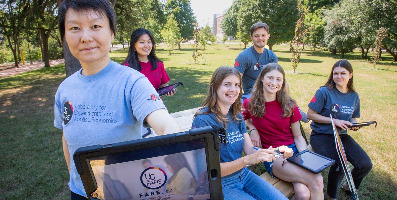 a faculty member holding a tablet with students in the background