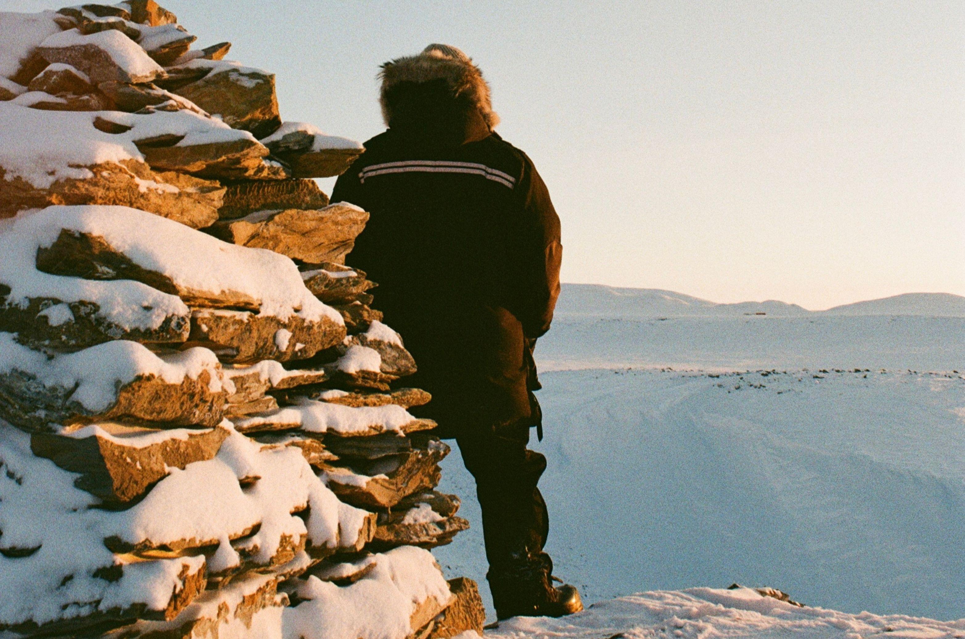 Mitchell, next to a pile of snowy rocks looks out over the icy expanse