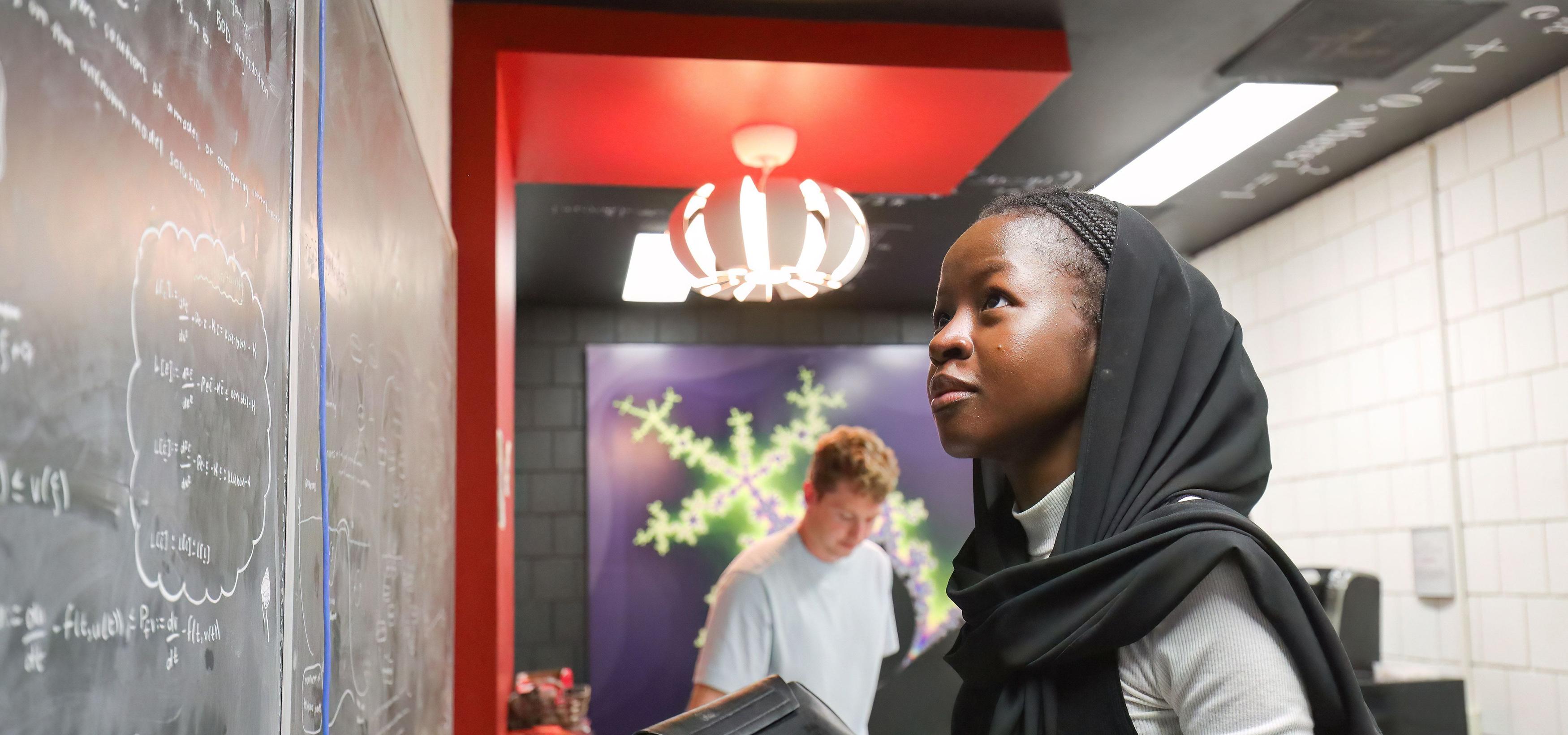 A math student looking at equations on a chalkboard
