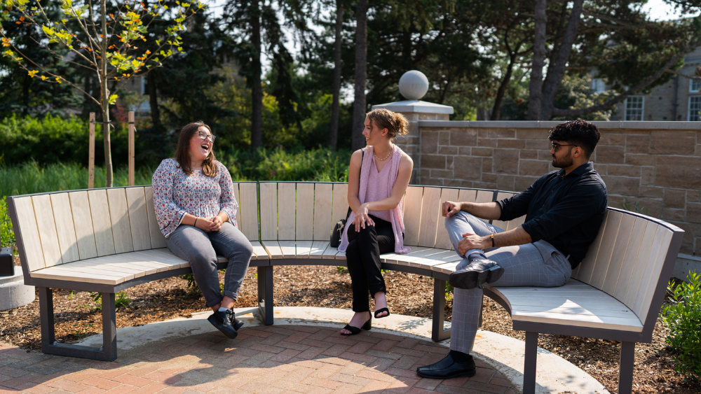 Three Lang students sitting on a bench in Lang Plaza