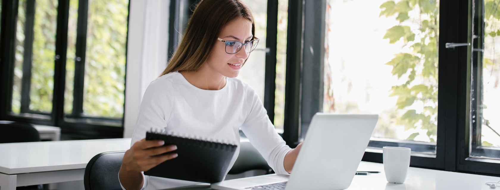 A student wearing glasses working on a laptop at a desk