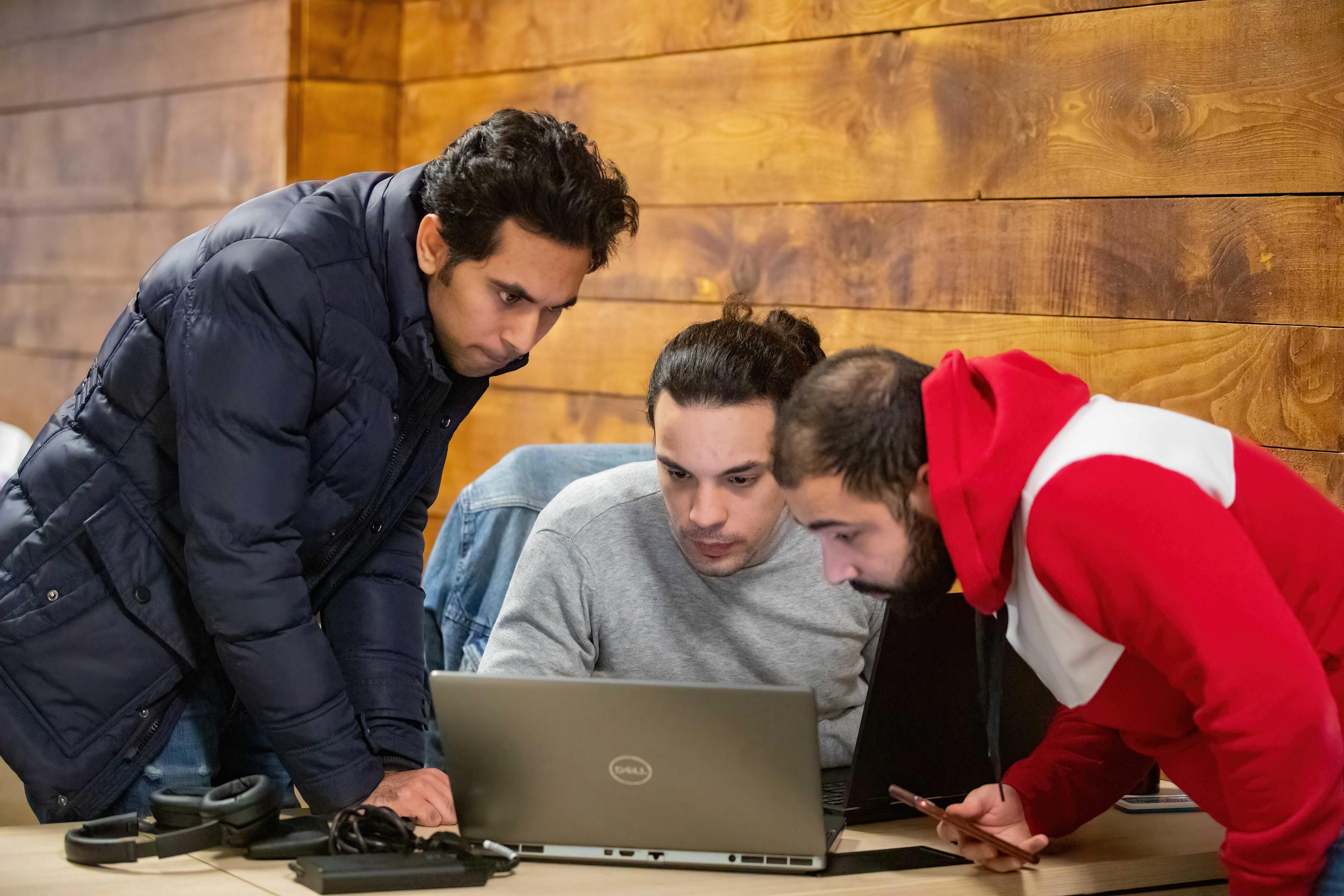 Three students looking into a laptop