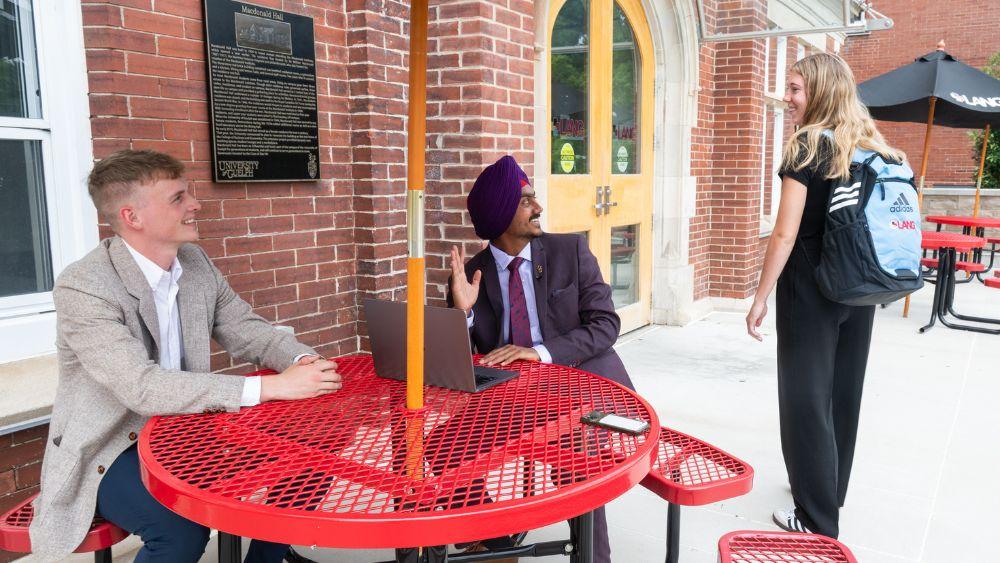 two people sitting outside of McDonald Hall and one walking inside
