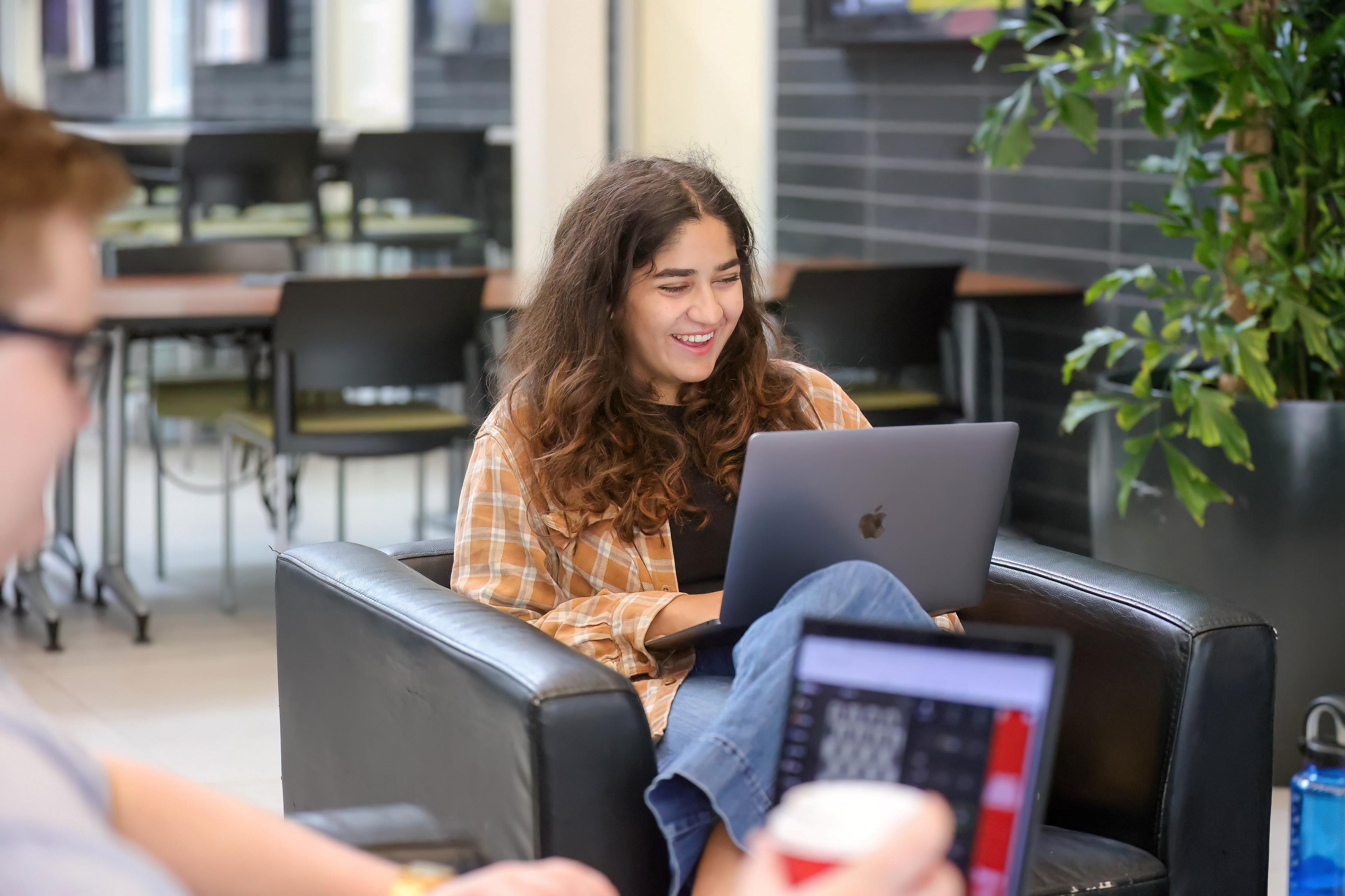Student studying and smiling in the Thornbrough Atrium.