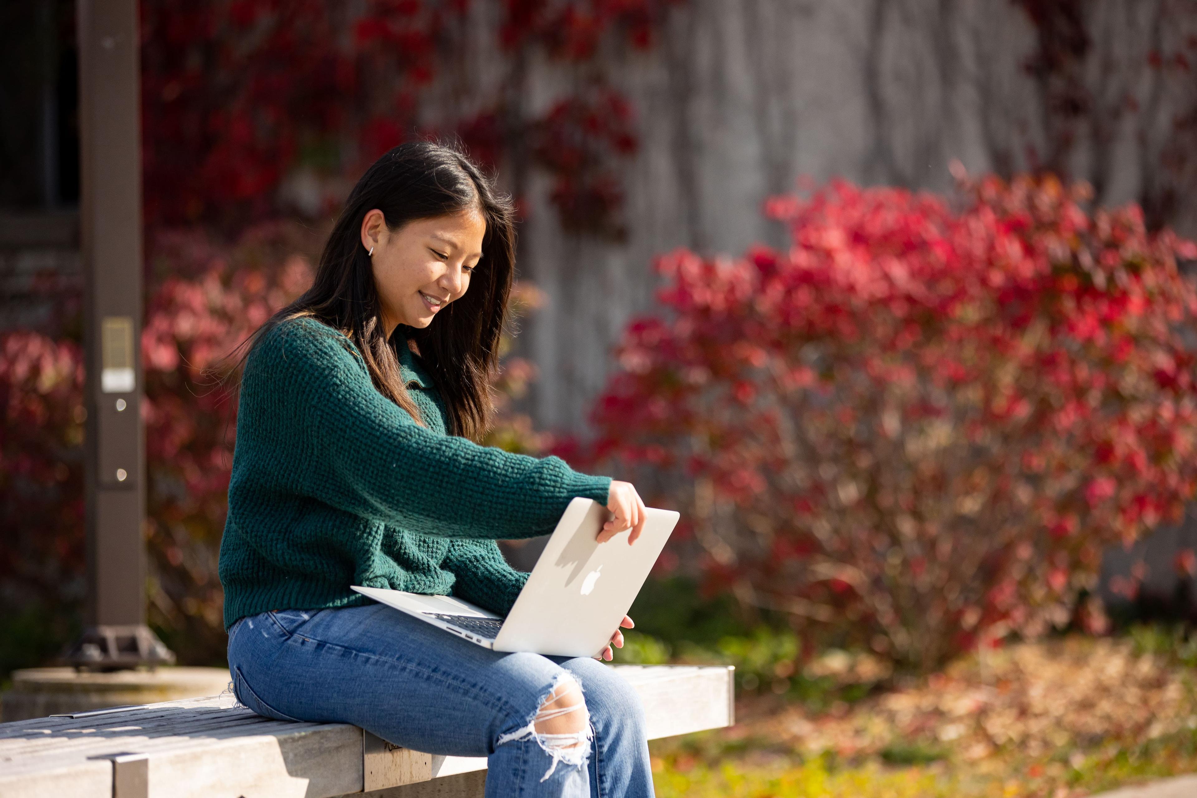 Student sitting at a bench looking at a laptop
