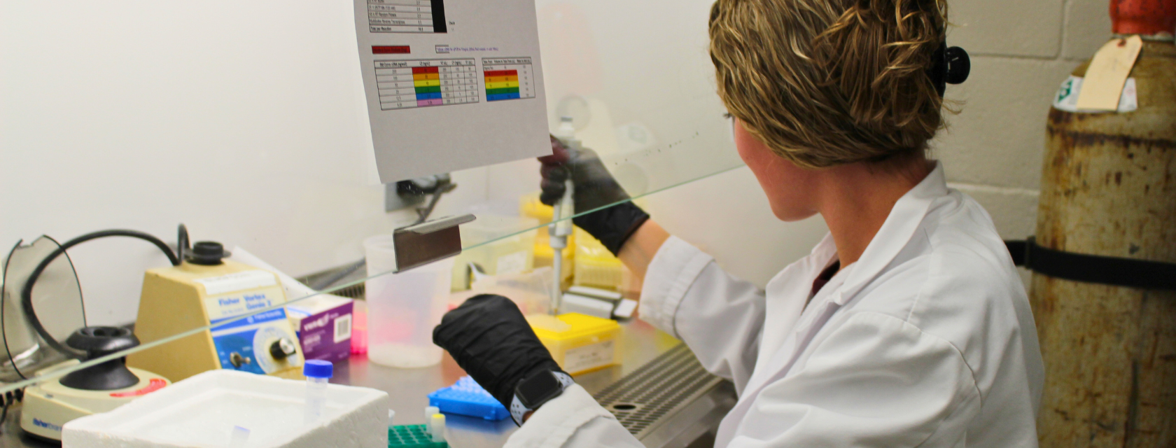 A student wearing a lab coat stands confidently, embodying professionalism and expertise in a scientific environment.