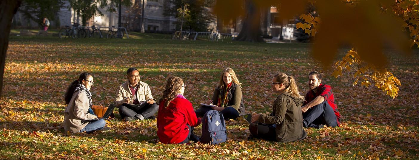 Students studying on grass in the Fall.