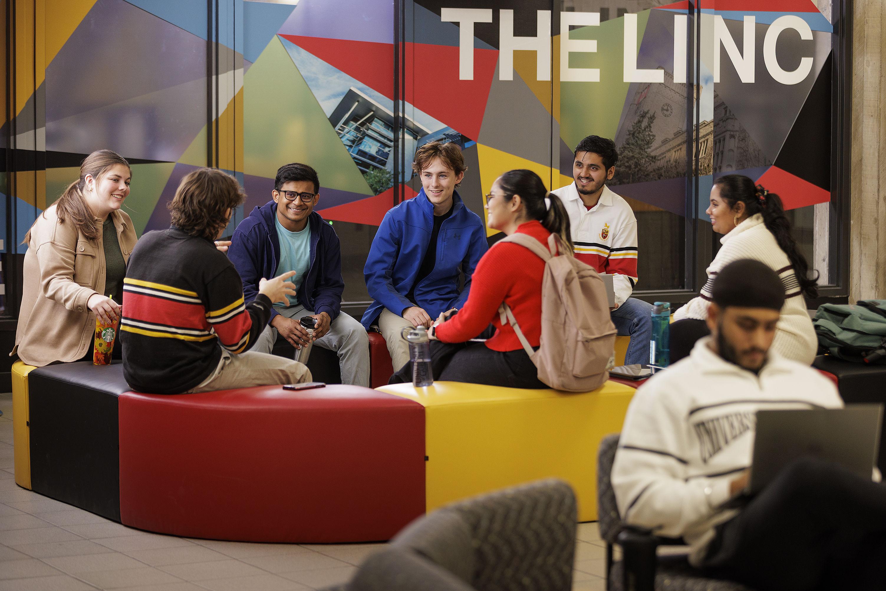 A group of students sitting outside the Lincoln Alexander Student Centre.