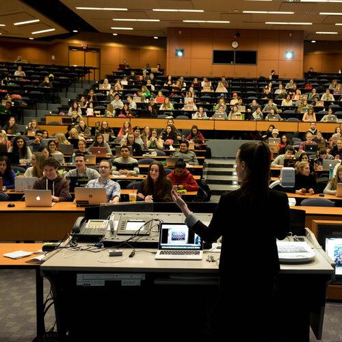 A professor lecturing in front of a class of students.