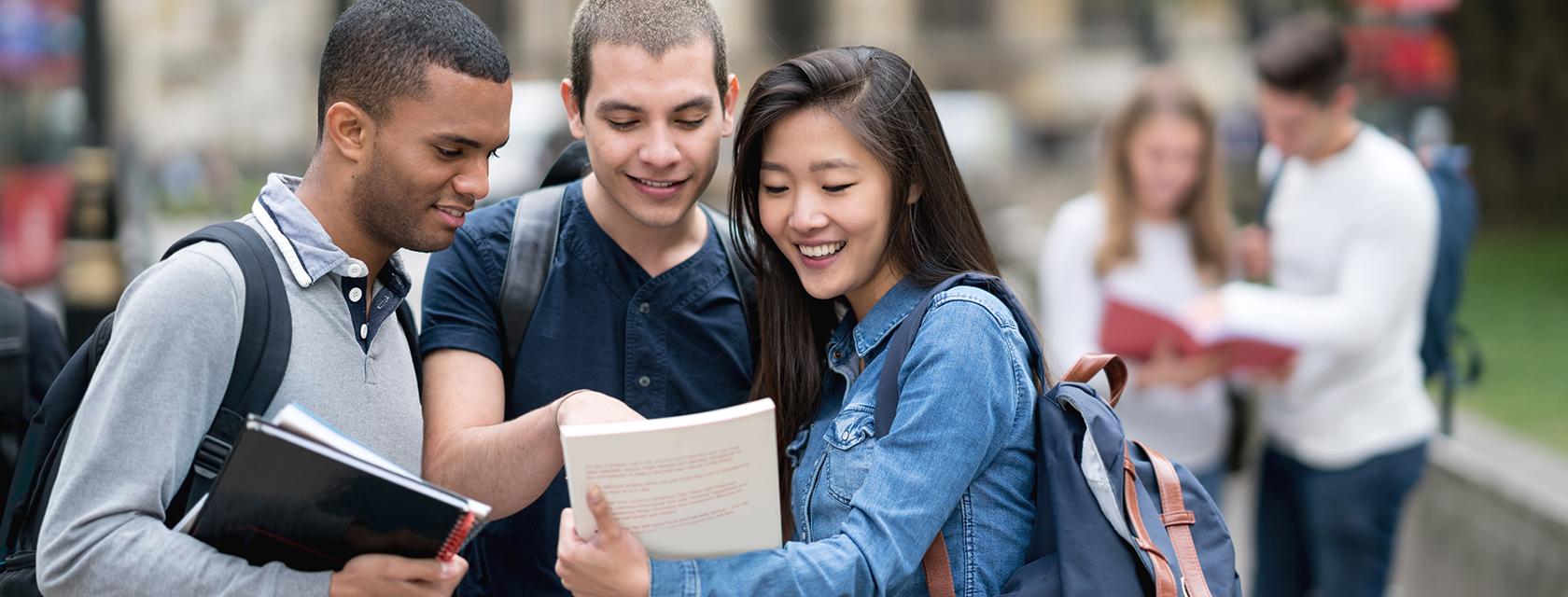 Group of international students looking at a book together.