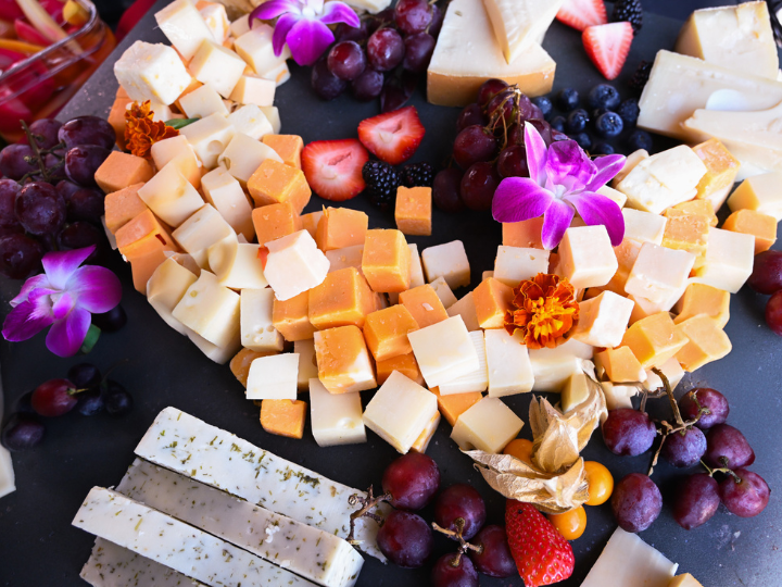 cheese board with grapes, berries and edible flowers.