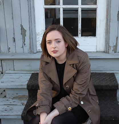 Woman sitting on the steps of an old house.