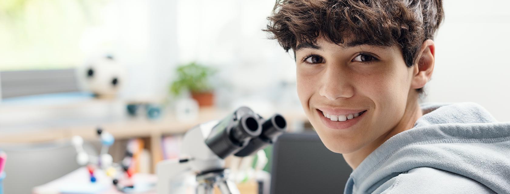Young male student with a microscope.