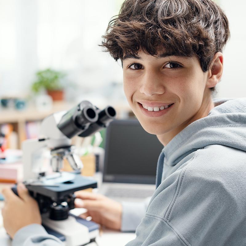 Young male student working on a microscope.