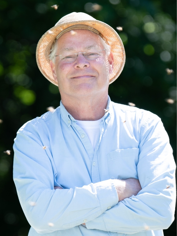 Paul Kelly stands proudly amongst a few flying honey bees