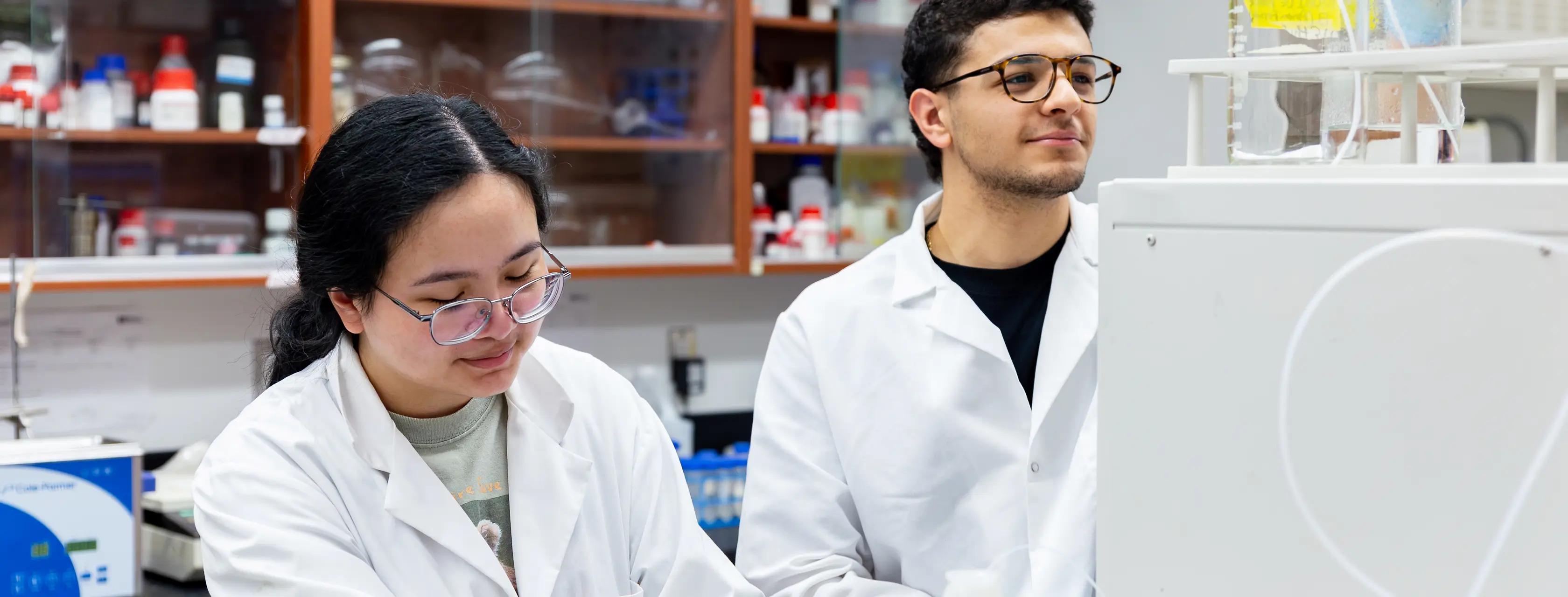 Two students in a lab looking at a computer.
