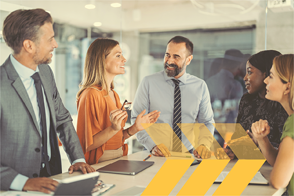 Group of men and women standing around a table listening to their manager.
