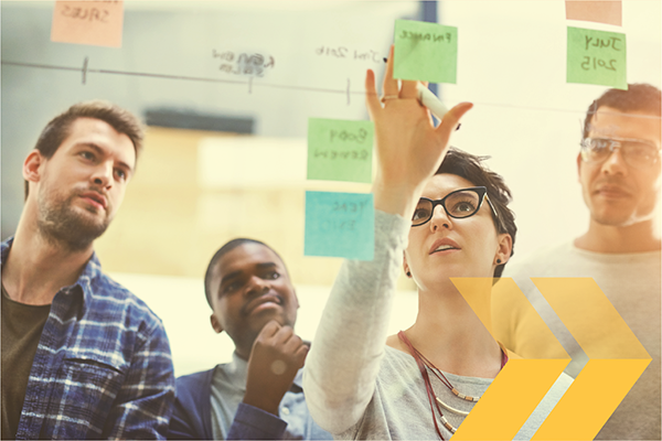 Small group of people adding sticky notes to a board.