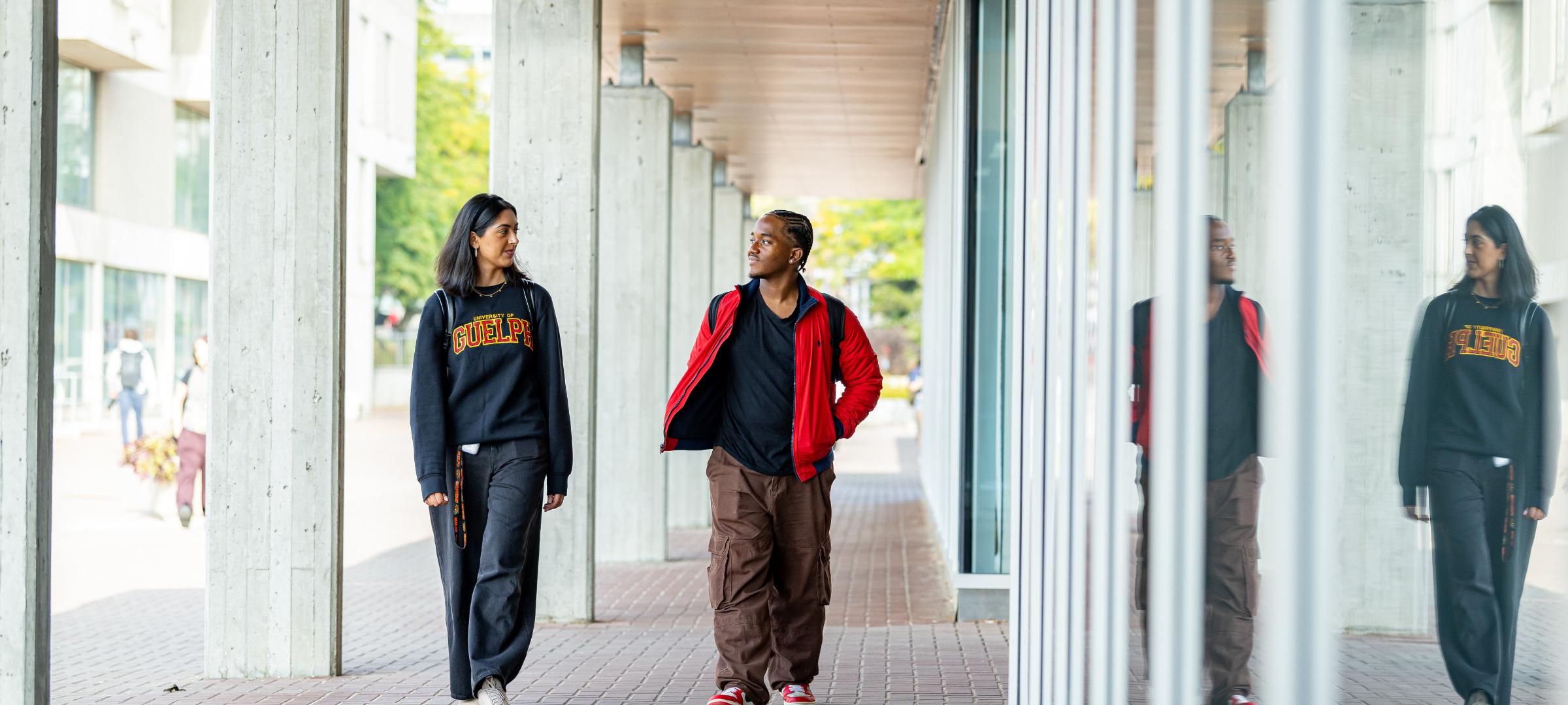Two students walking and talking on campus outside the Thornbrough building. 