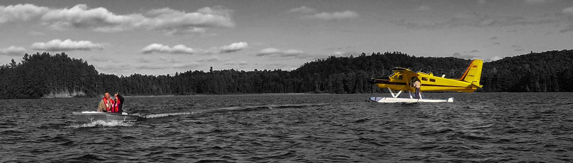A yellow plane two people on a speedboat in a red lifejacket