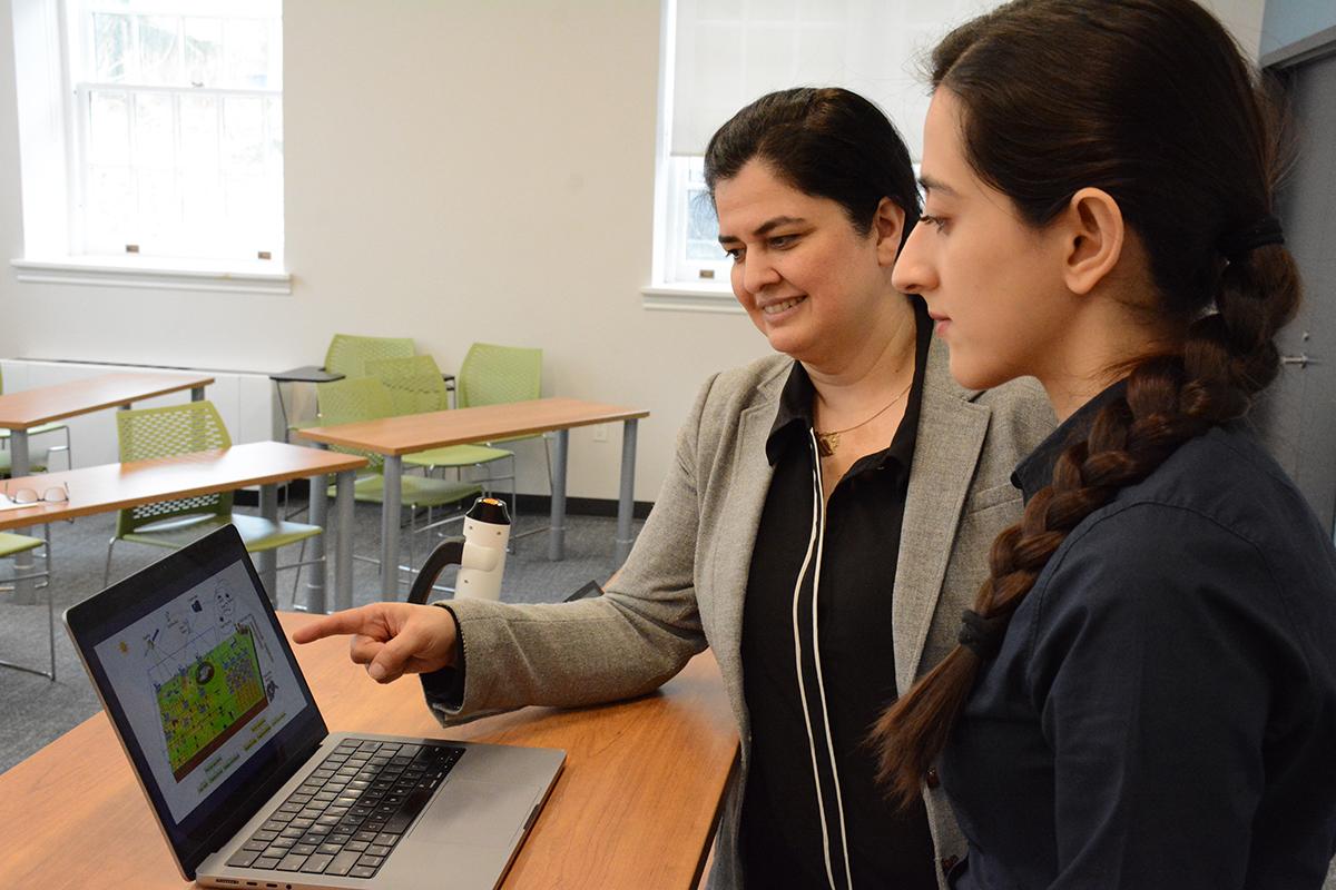 Two woman looking and pointing at a laptop