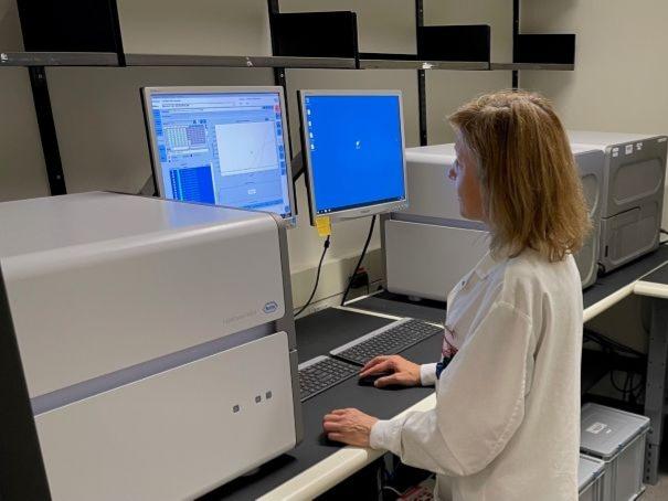 A woman in a lab coat at the animal health laboratory checks information on a screen