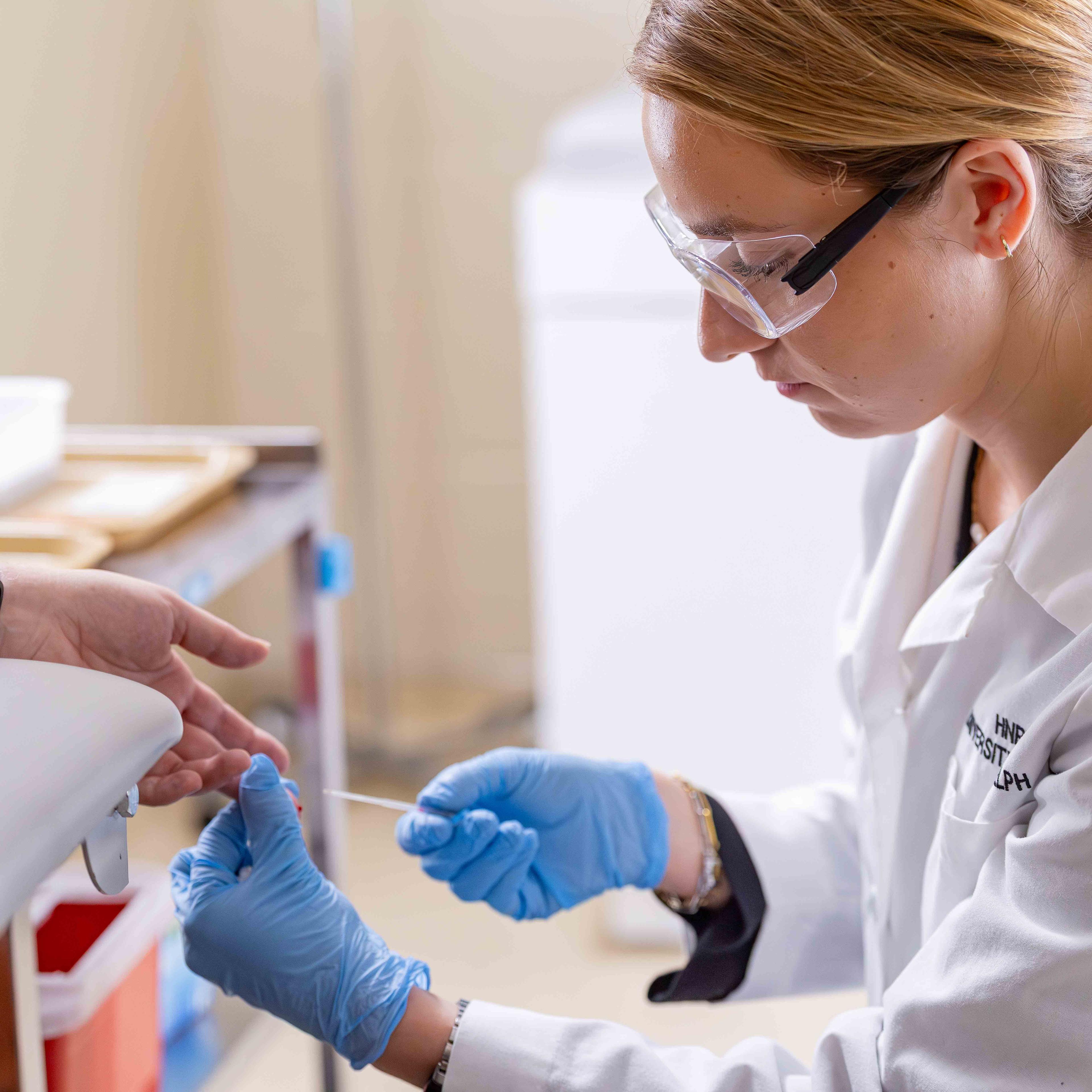 Student takes a fingerprick for a blood glucose test