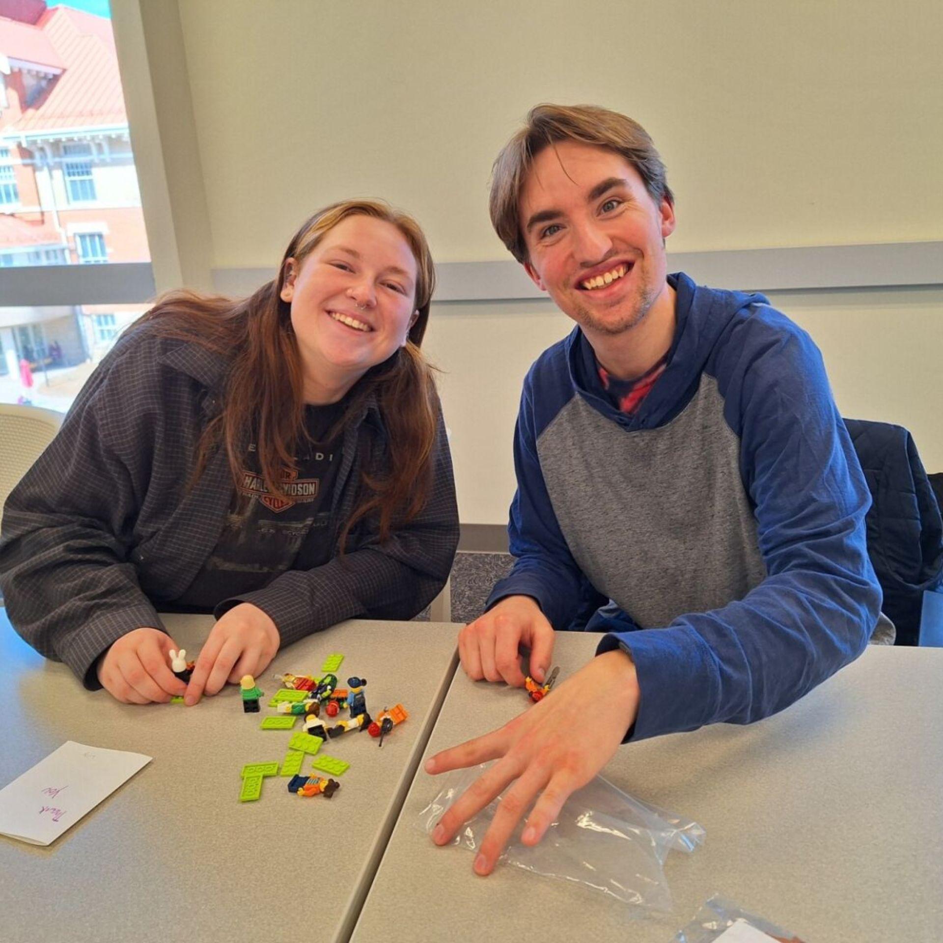 A student and a volunteer smile, working on a puzzle together.