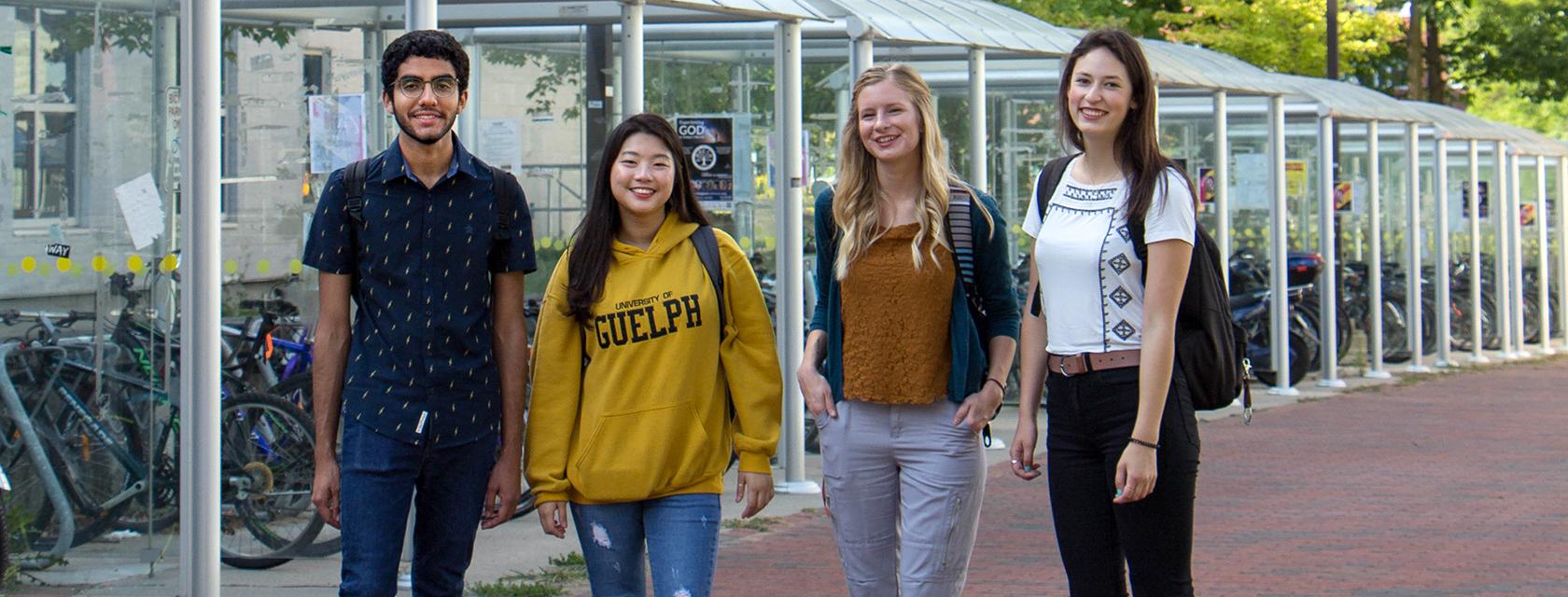 Group of four English Language Programs students standing near the bike racks on campus.