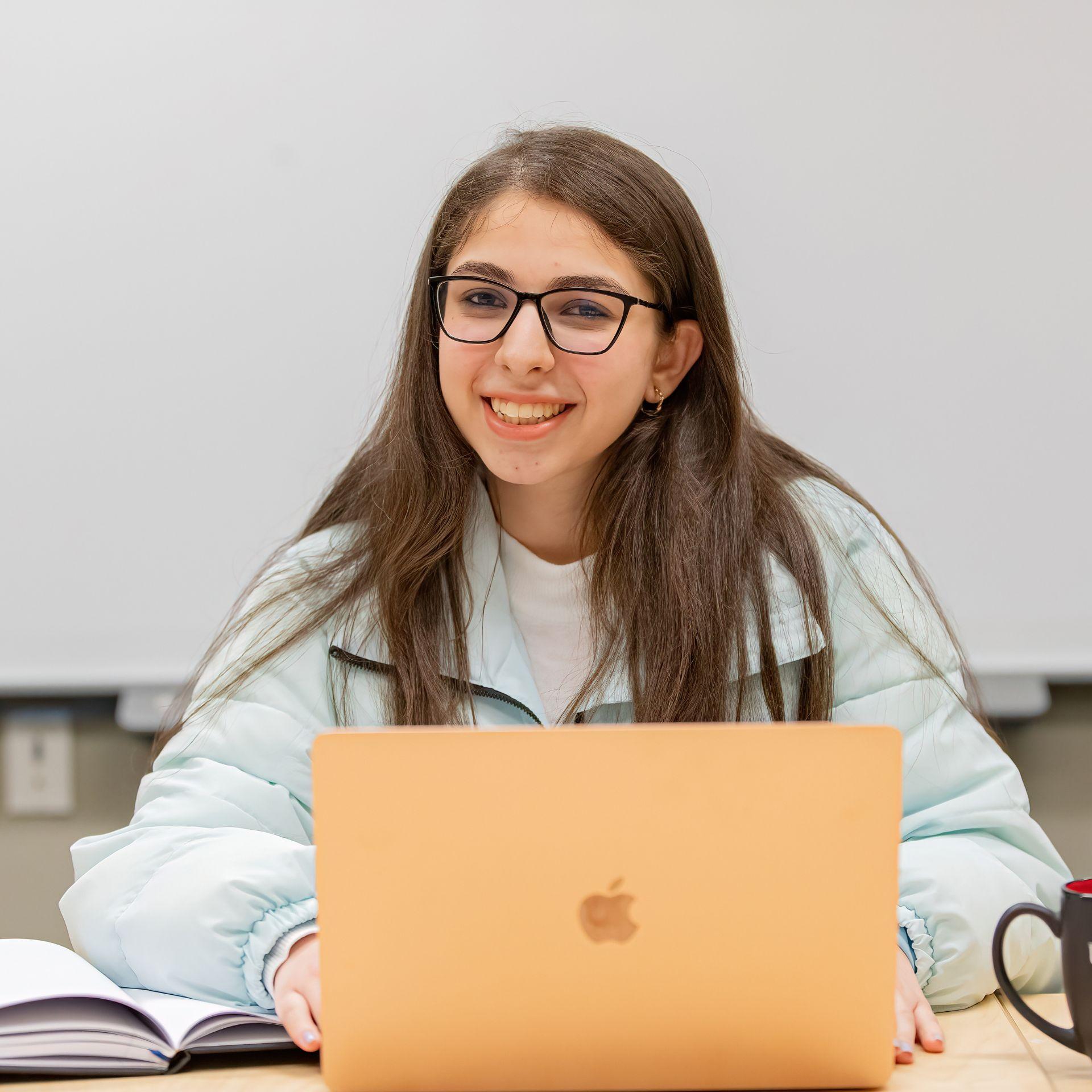 A student working on their laptop smiles.