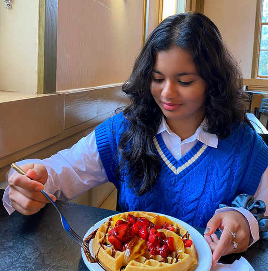 anushka about to eat a large belgium waffle with strawberries on it