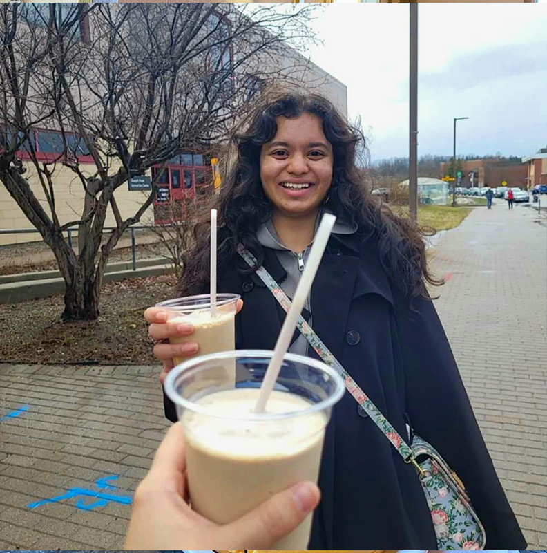 anushka holding a creamy iced drink and the friend taking the photo is cheering her