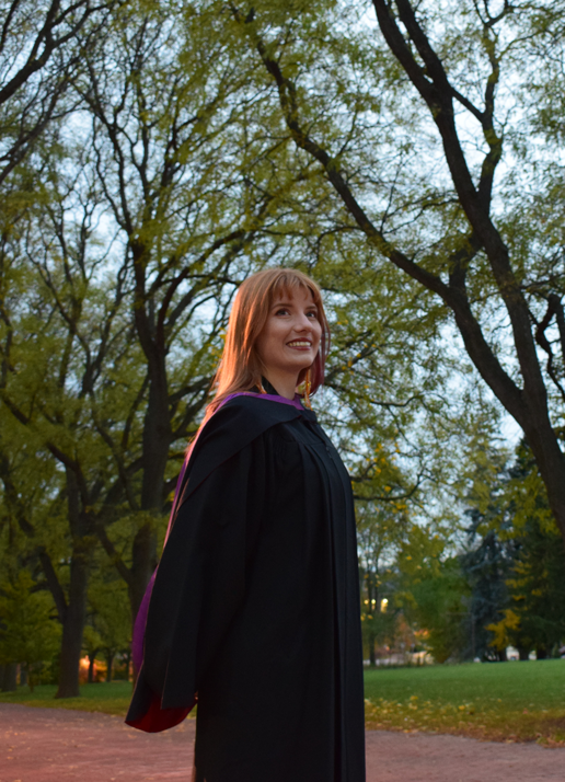ava standing on campus wearing a graduation gown