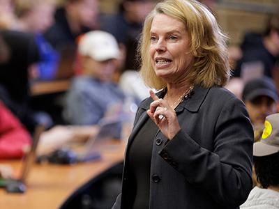 Female leader addressing students in a lecture hall.