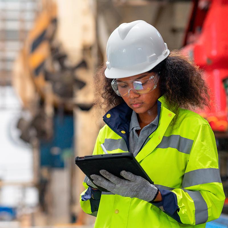 Young woman in a hard had working in a manufacturing setting.
