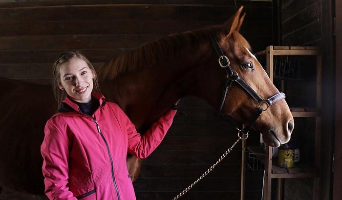 Young woman in a barn with her horse.
