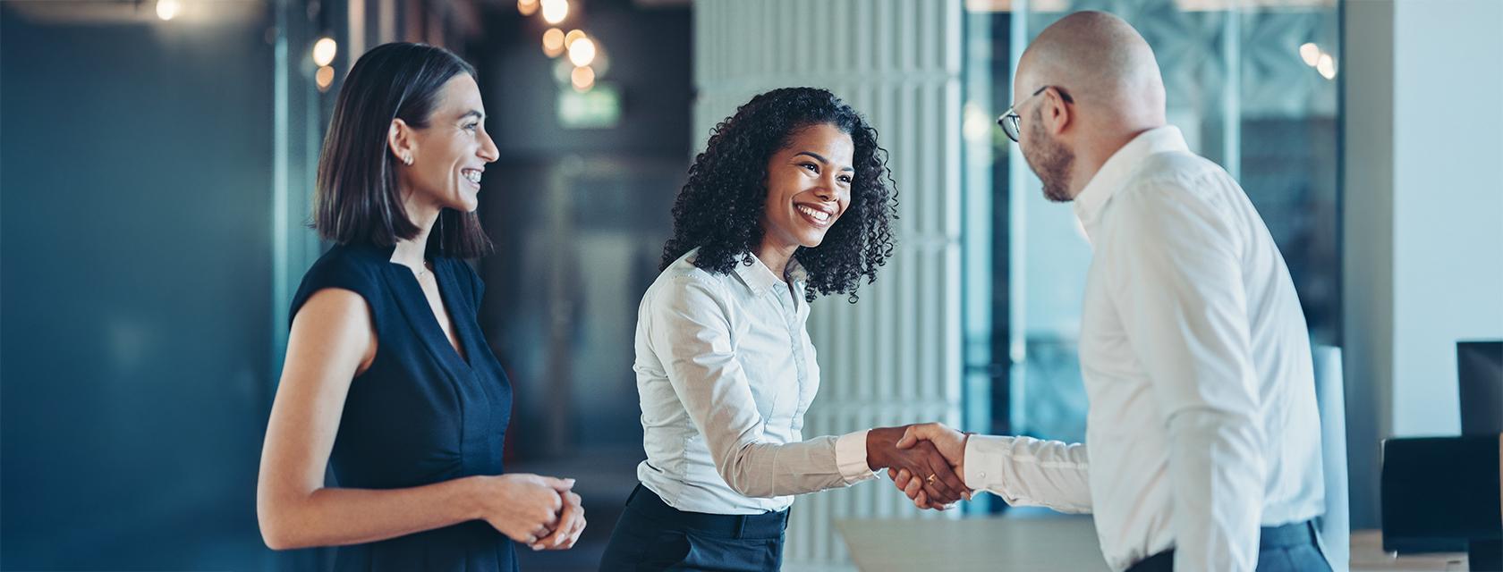 Smiling professional female shaking hands with a male colleague.