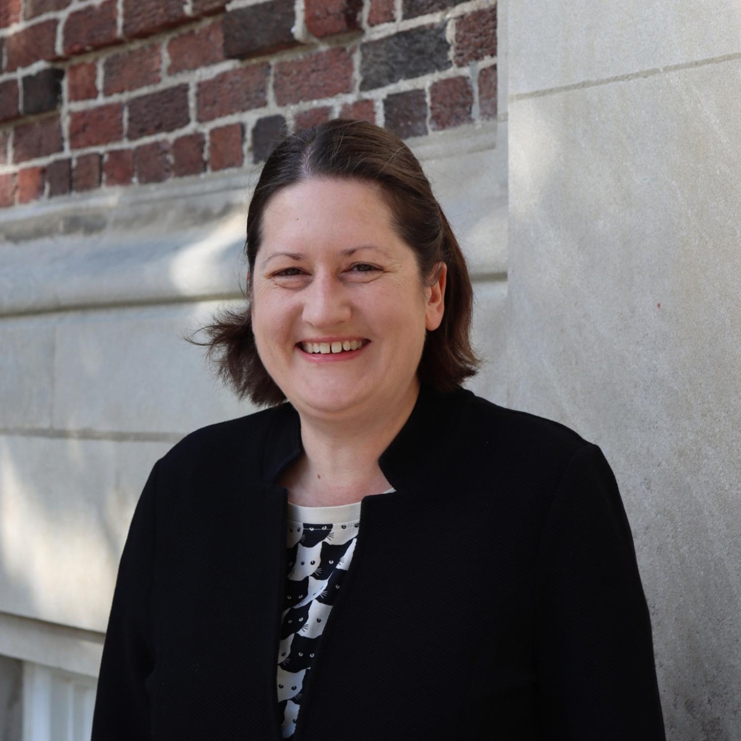 caucasian woman with short brown hair and brown eyes, smiling for a professional headshot.