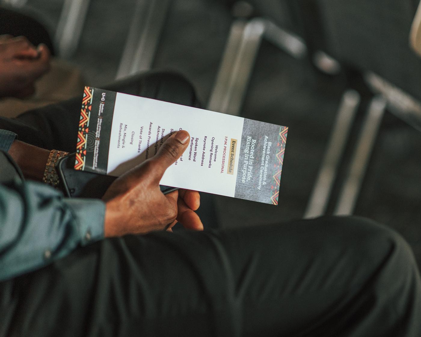 Close-up of hand holding an event program for the Black Graduation and Achievement Ceremony