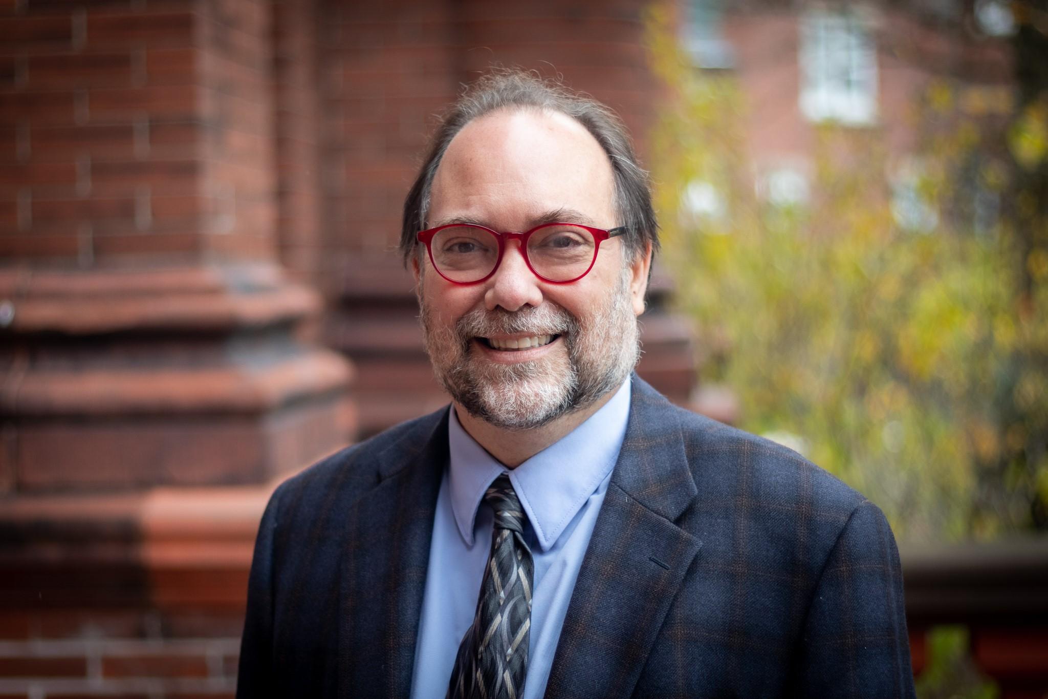 A headshot of Byron Sheldrick in a suit and tie