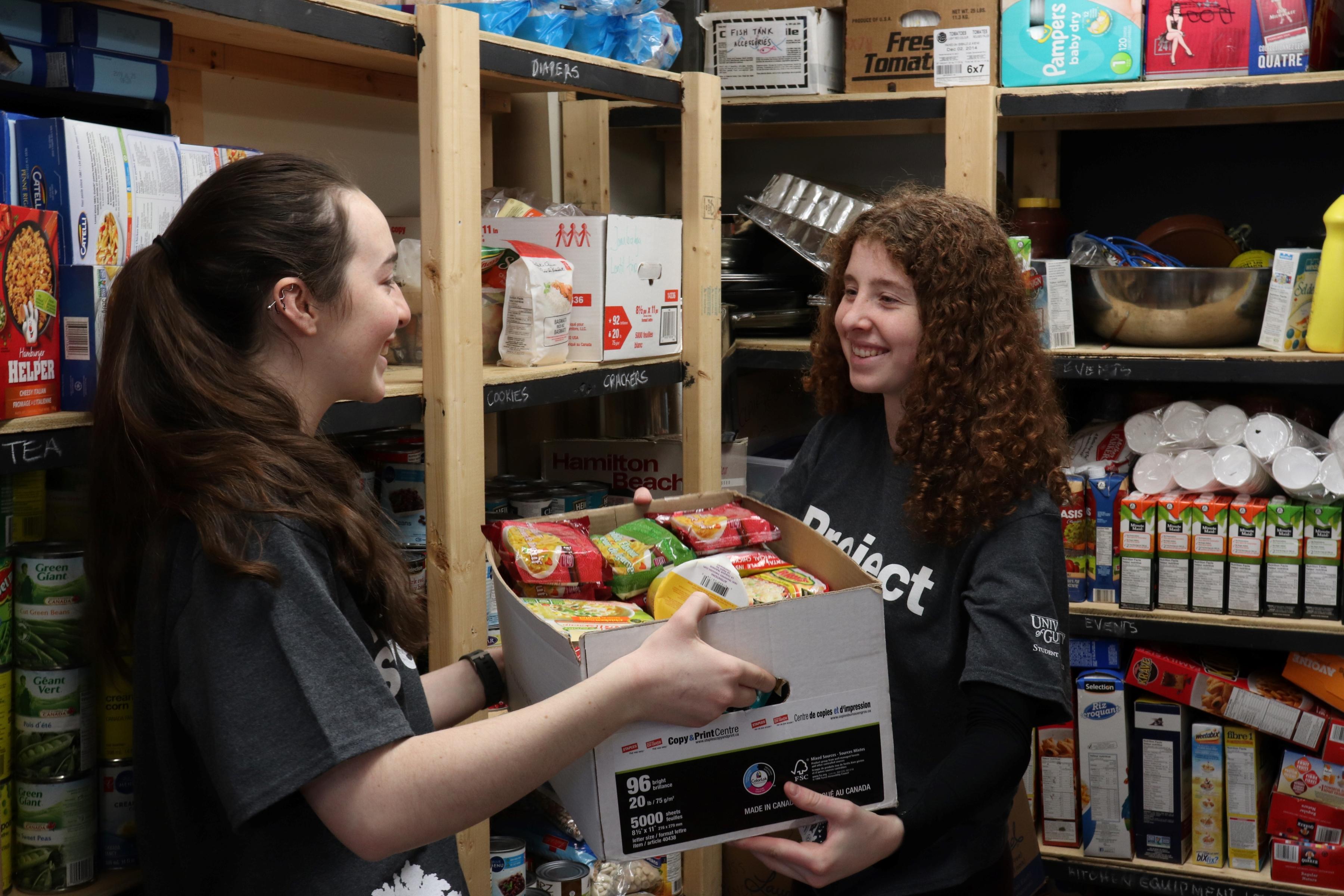 two people carrying box of food